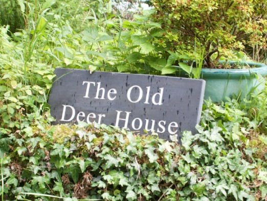 The Old Deer House sign in a hedge
